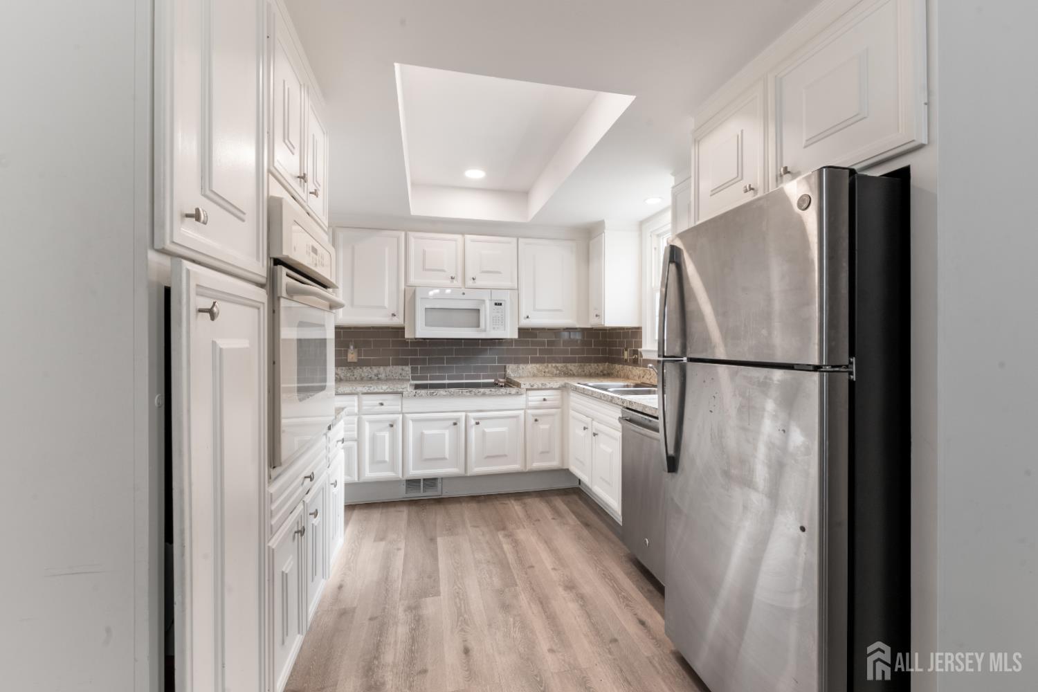 94 Gloucester Way, Unit B Monroe Township, NJ 08831 - Photo 8 of 20 a kitchen with a refrigerator a sink and dishwasher a refrigerator with white cabinets
