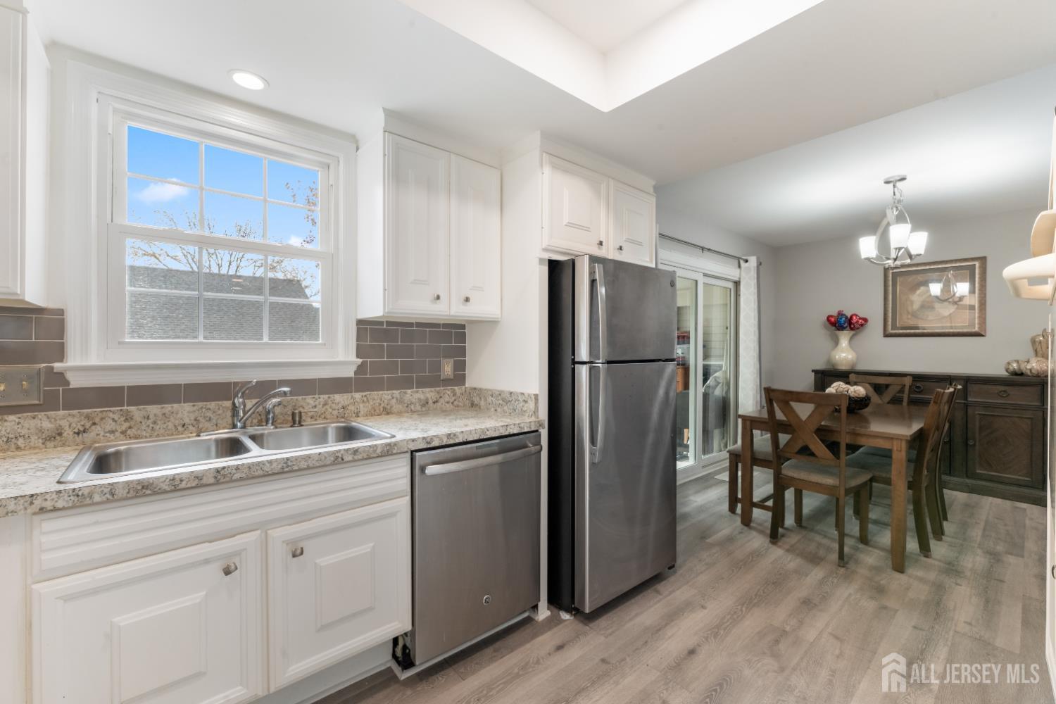 94 Gloucester Way, Unit B Monroe Township, NJ 08831 - Photo 10 of 20 a kitchen with refrigerator cabinets dining table and chairs