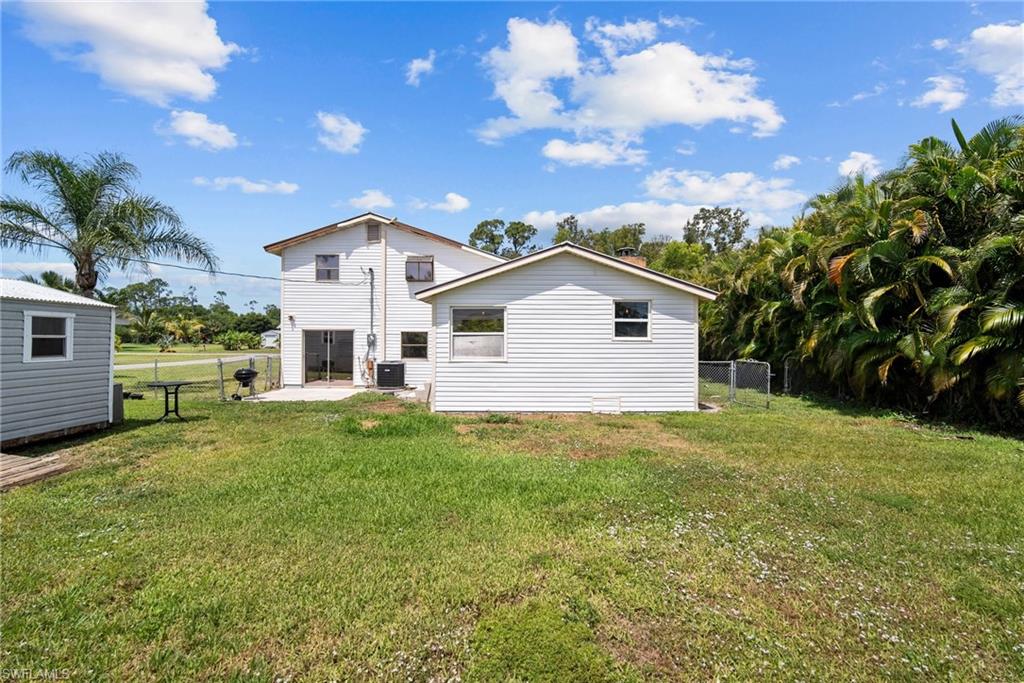 19883 Bristol Road Fort Myers, FL 33908 - Photo 24 of 25 Rear view of property with a patio, central AC unit, and a lawn