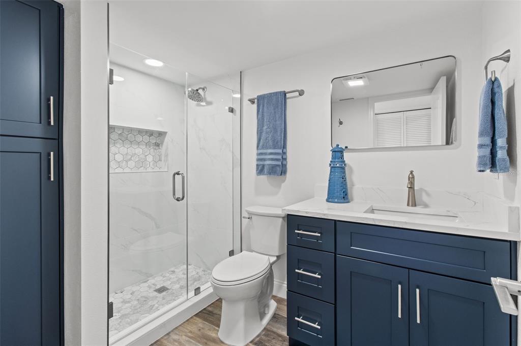 14950 Gulf Boulevard, Unit 503 Madeira Beach, FL 33708 - Photo 23 of 43 a bathroom with a toilet a sink a glass door a shower a mirror and vanity