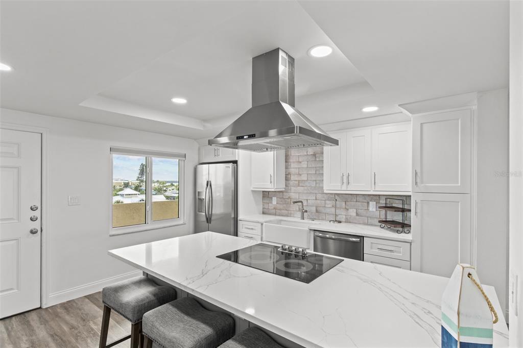 14950 Gulf Boulevard, Unit 503 Madeira Beach, FL 33708 - Photo 4 of 43 a kitchen with stainless steel appliances kitchen island granite countertop a sink dishwasher a stove a refrigerator a dining table and chairs with wooden floor