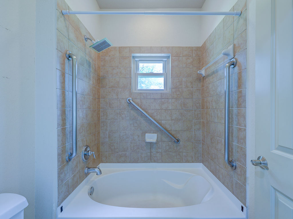 9707 Anderson Mill Road, Unit 22 Austin, TX 78750 - Photo 36 of 39 A well-lit shower area provides safety with grab bars and natural light from a charming window.