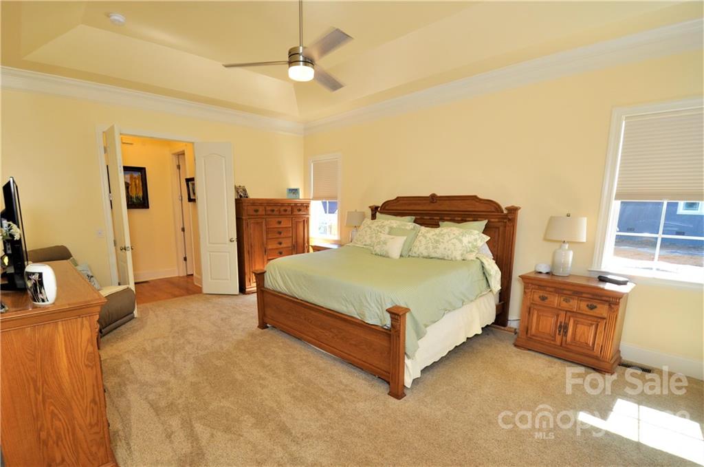 186 Chaska Loop Troutman, NC 28166 - Photo 16 of 48 a spacious bedroom with a bed and wooden floor