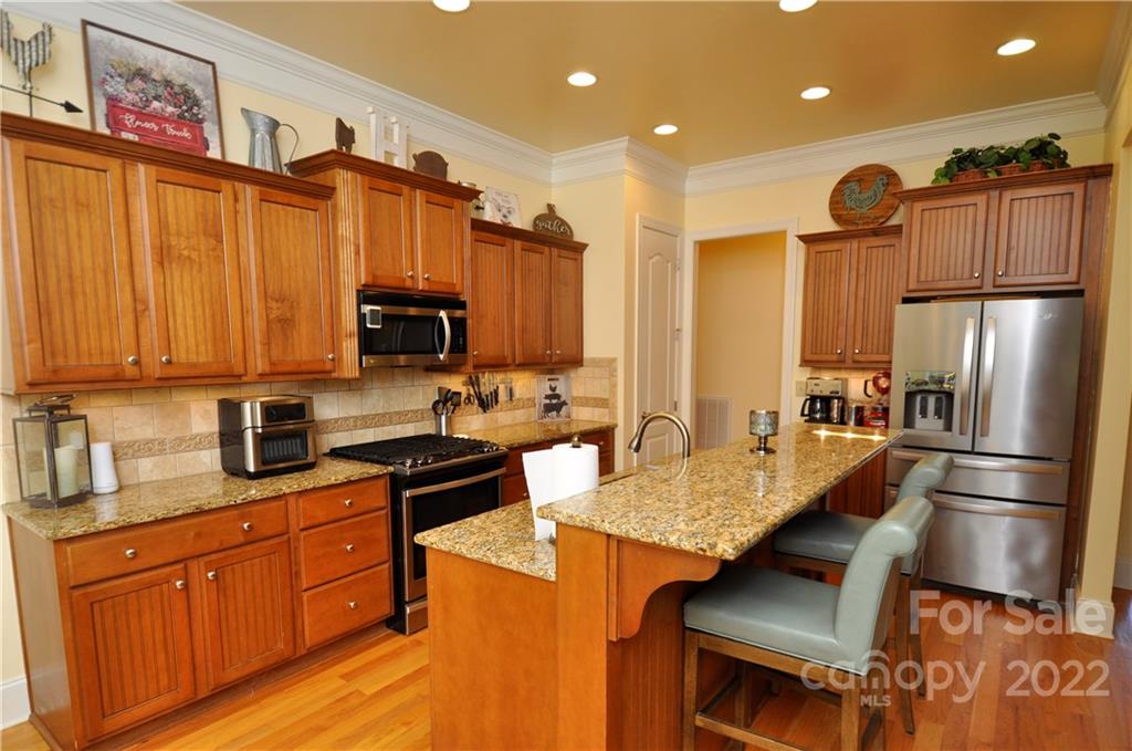 186 Chaska Loop Troutman, NC 28166 - Photo 27 of 48 a kitchen with stainless steel appliances granite countertop a refrigerator a stove and a sink with wooden floors