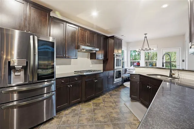 a large kitchen with stainless steel appliances cabinets a sink and a large window