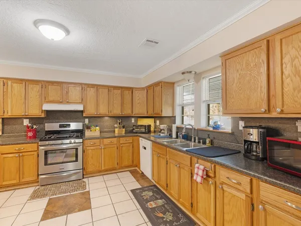 a kitchen with stainless steel appliances a sink counter space cabinets and a large window