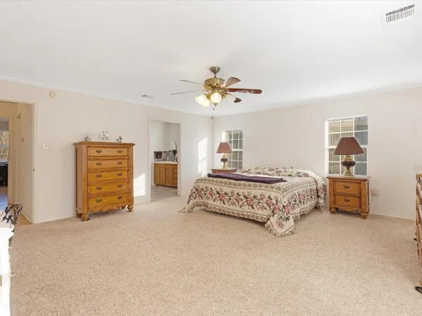 a spacious bedroom with a bed a dresser and a chandelier
