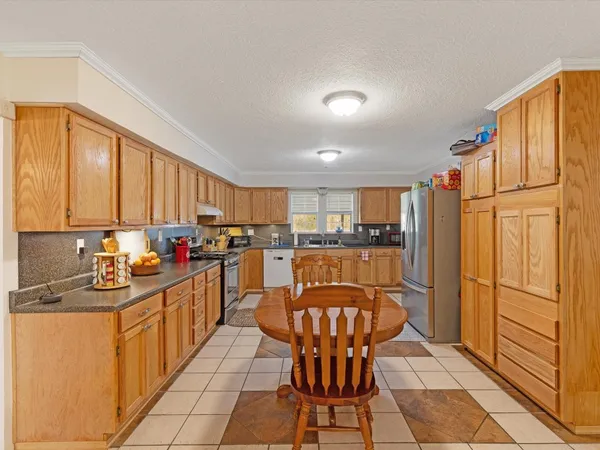 a kitchen with stainless steel appliances granite countertop a refrigerator a sink dishwasher a dining table and chairs with wooden floor