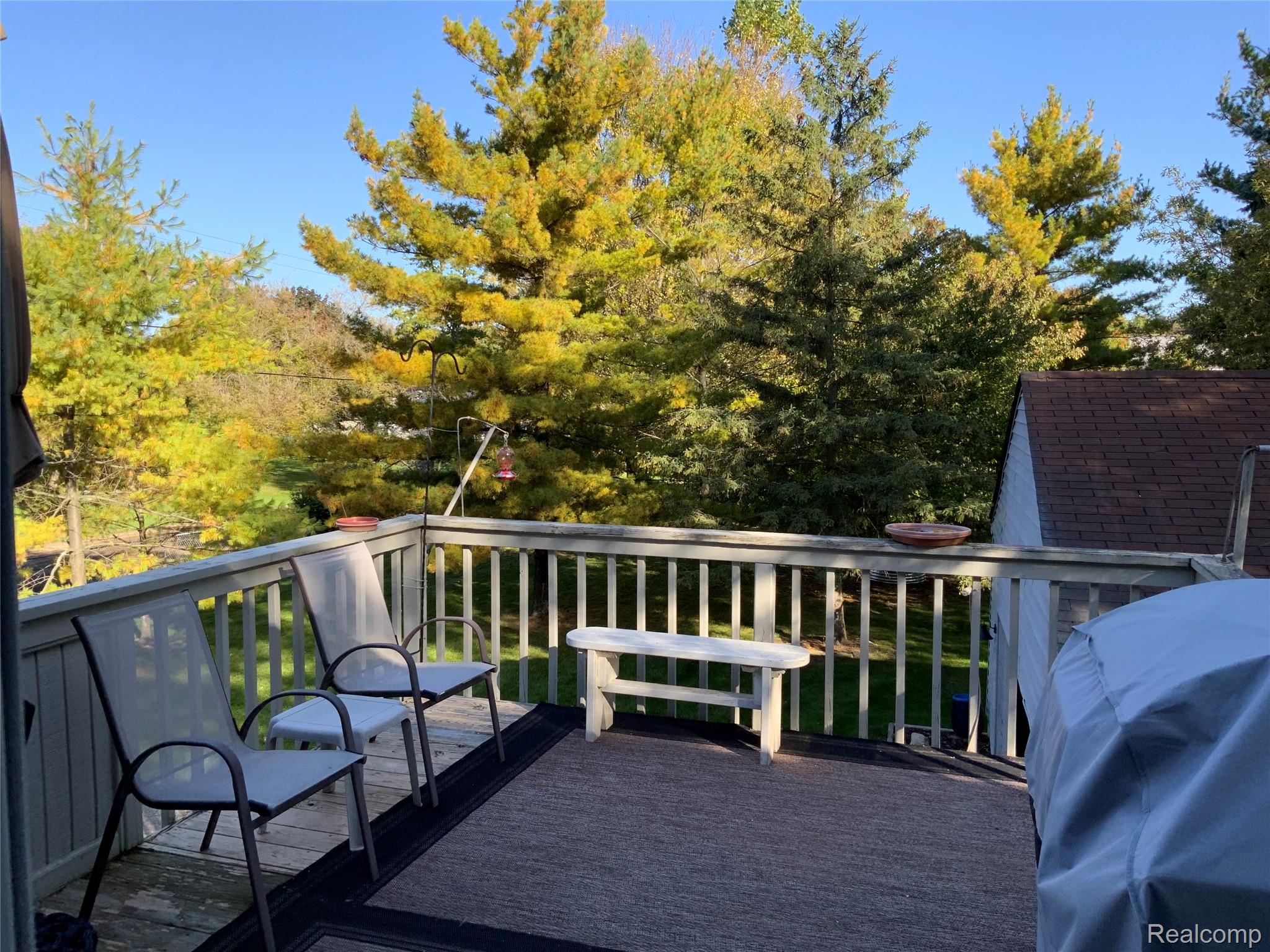 3828 Morgan Road Lake Orion, MI 48359 - Photo 14 of 39 Outdoor deck with wood railings, expansive tree canopy, and a pitched roof structure