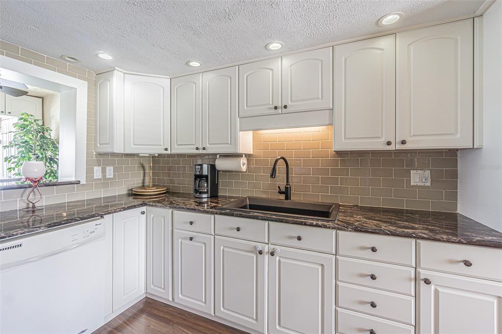 1 Windrush Boulevard, Unit 54 Indian Rocks Beach, FL 33785 - Photo 4 of 37 a kitchen with granite countertop white cabinets white appliances and sink