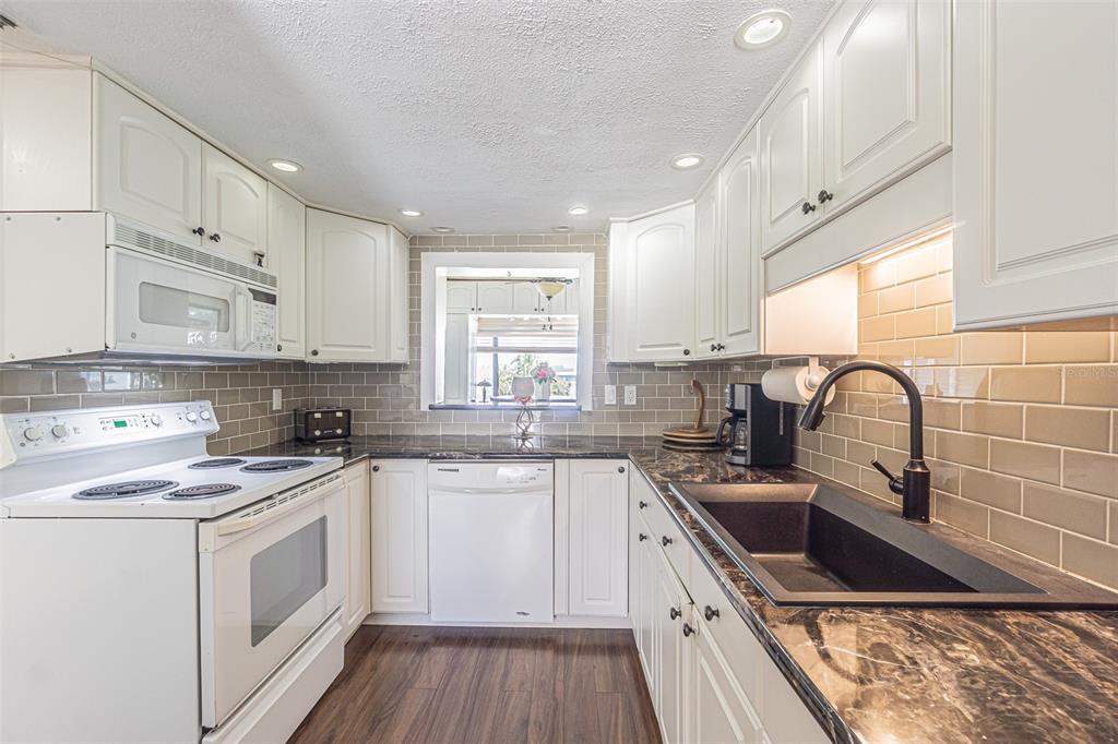 1 Windrush Boulevard, Unit 54 Indian Rocks Beach, FL 33785 - Photo 8 of 37 a kitchen with white cabinets sink and white appliances