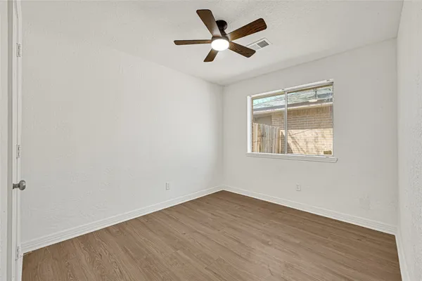 an empty room with wooden floor and ceiling fan