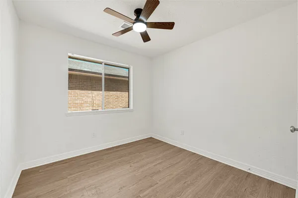 an empty room with a window and a fan