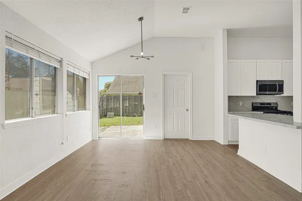 a view of an empty room with a window and wooden floor