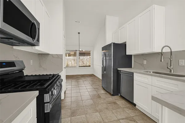 a kitchen with stainless steel appliances granite countertop a stove a refrigerator and a sink