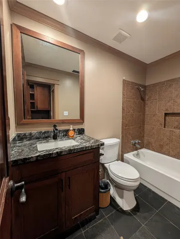 a bathroom with a granite countertop toilet sink and mirror