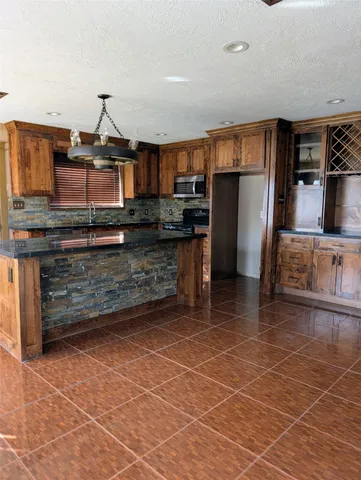 a kitchen with stainless steel appliances kitchen island granite countertop a refrigerator and a stove top oven