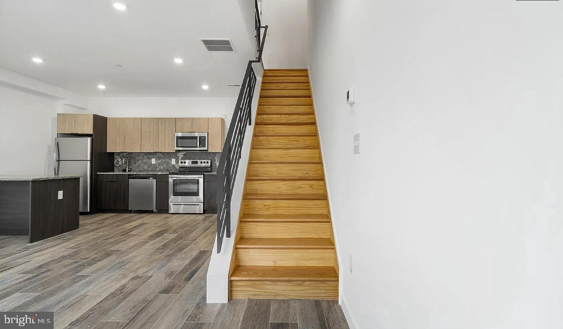 300 Budd Street, Unit D2 Philadelphia, PA 19104 - Photo 16 of 23 a kitchen with stainless steel appliances a refrigerator and a wooden floor