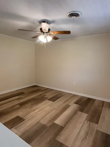 a view of a room with a ceiling fan and wooden floor