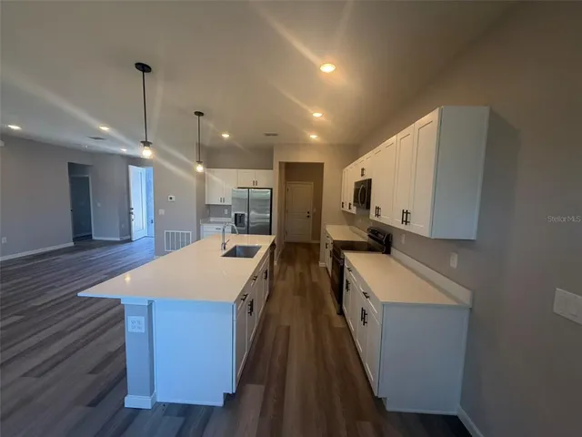 a large kitchen with a large counter top a sink a refrigerator and a stove