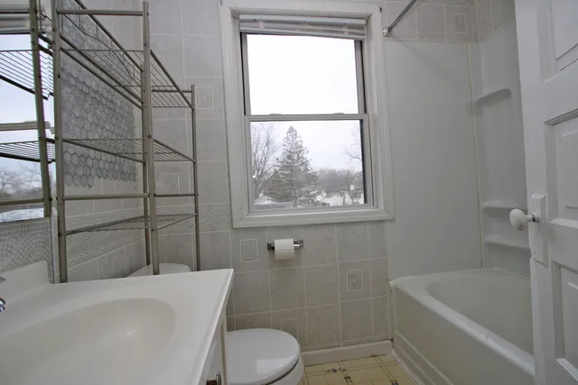a bathroom with a toilet a bath tub and a window