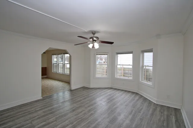 a view of an empty room with a window and wooden floor