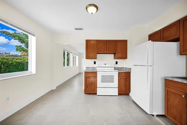 a kitchen with stainless steel appliances a stove top oven a sink a refrigerator and a window