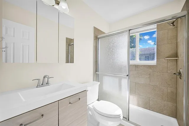 a bathroom with a sink a mirror a toilet and shower