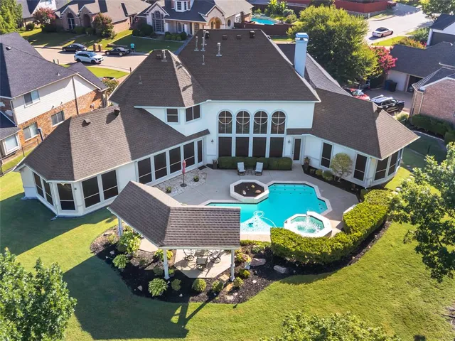 an aerial view of a house with swimming pool and a yard