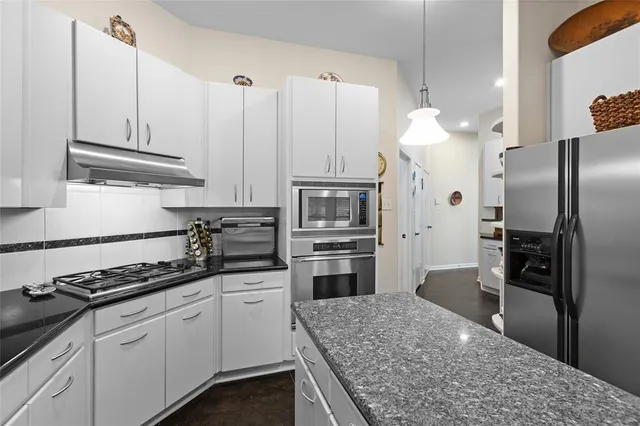 a kitchen with stainless steel appliances granite countertop a refrigerator a stove and a sink