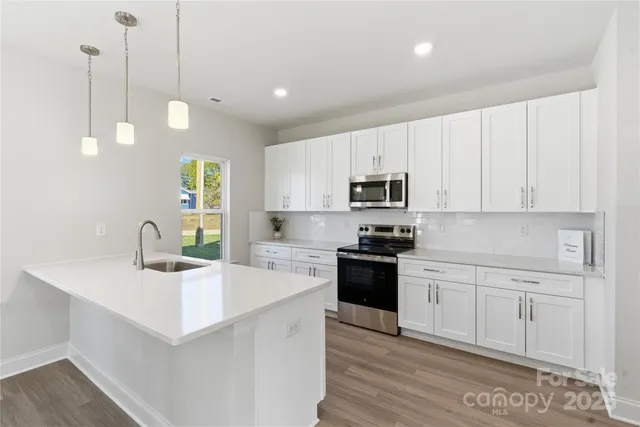 a kitchen with stainless steel appliances kitchen island granite countertop a sink a stove and cabinets