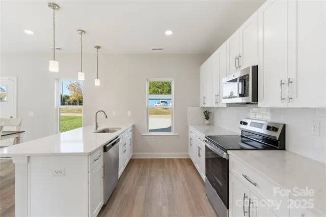 a kitchen with stainless steel appliances a sink a stove top oven a counter space and cabinets