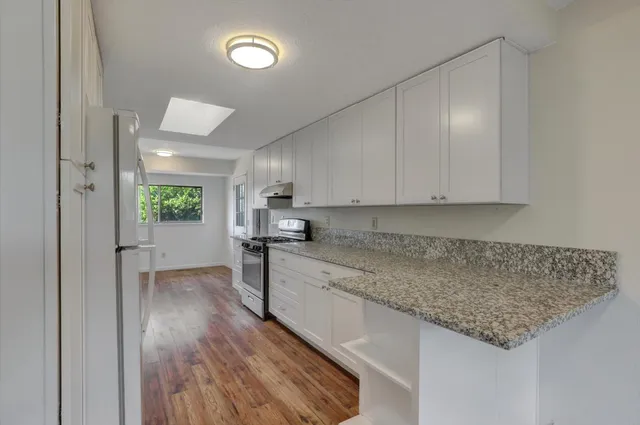 a kitchen with granite countertop kitchen island a sink stainless steel appliances and cabinets