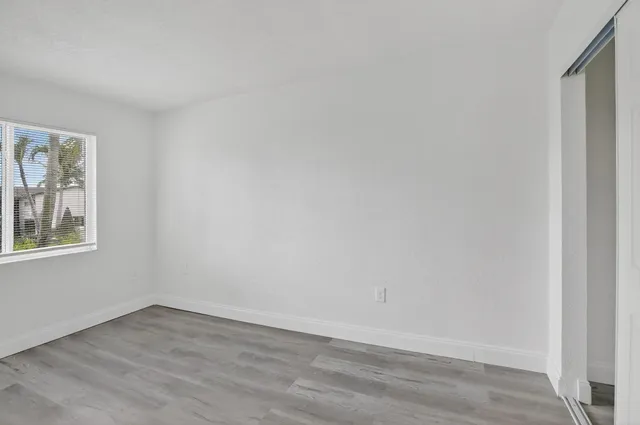 a view of an empty room with wooden floor and a window