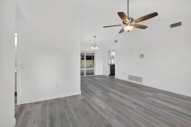 a view of empty room with wooden floor and ceiling fan