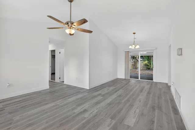 a view of a room with wooden floor a ceiling fan and windows