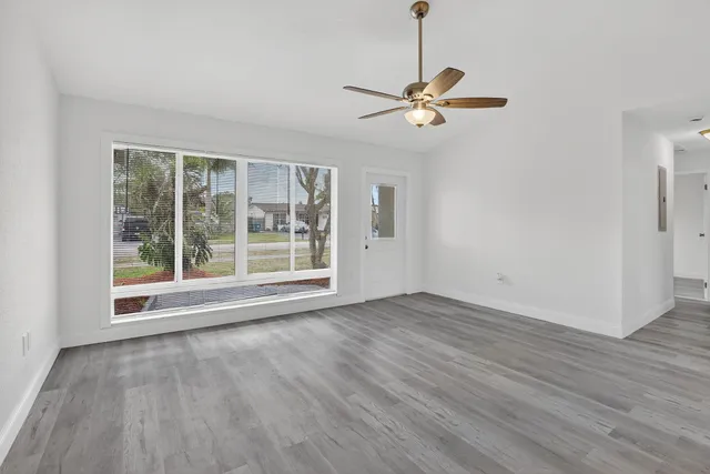 a view of empty room with wooden floor fan and window