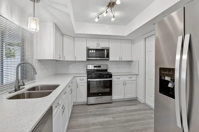 a kitchen with granite countertop a refrigerator stove and sink