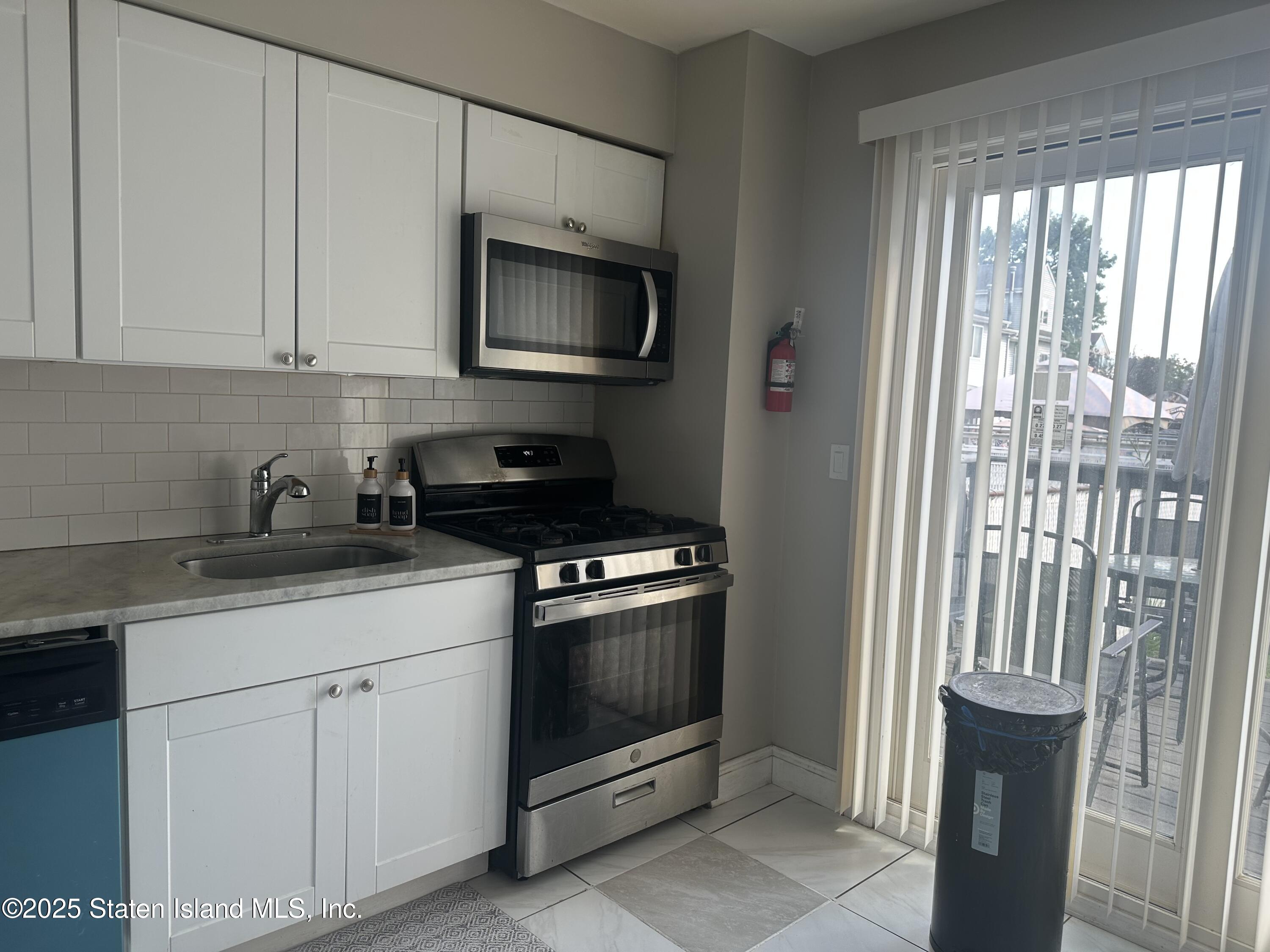 12 Delmar Avenue, Unit A Staten Island, NY 10312 - Photo 3 of 19 a kitchen with white cabinets and black appliances