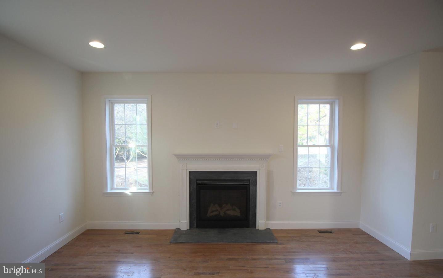 220 Fairview Road Glenmoore, PA 19343 - Photo 6 of 14 an empty room with wooden floor a fireplace and windows