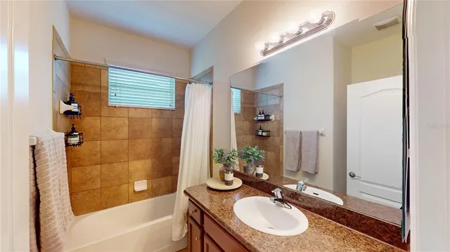 a bathroom with a granite countertop sink a mirror a bathtub and shower