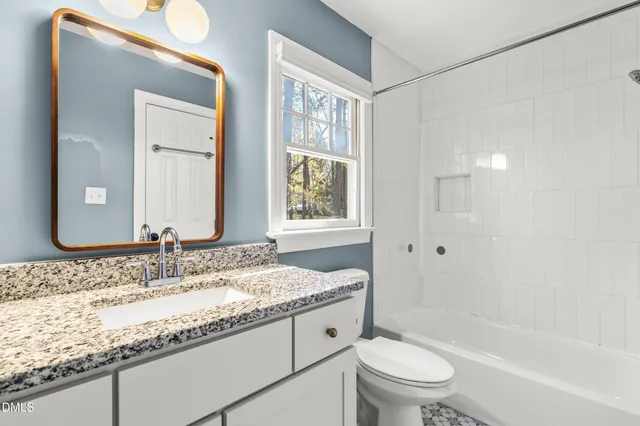 a bathroom with a granite countertop toilet sink and mirror