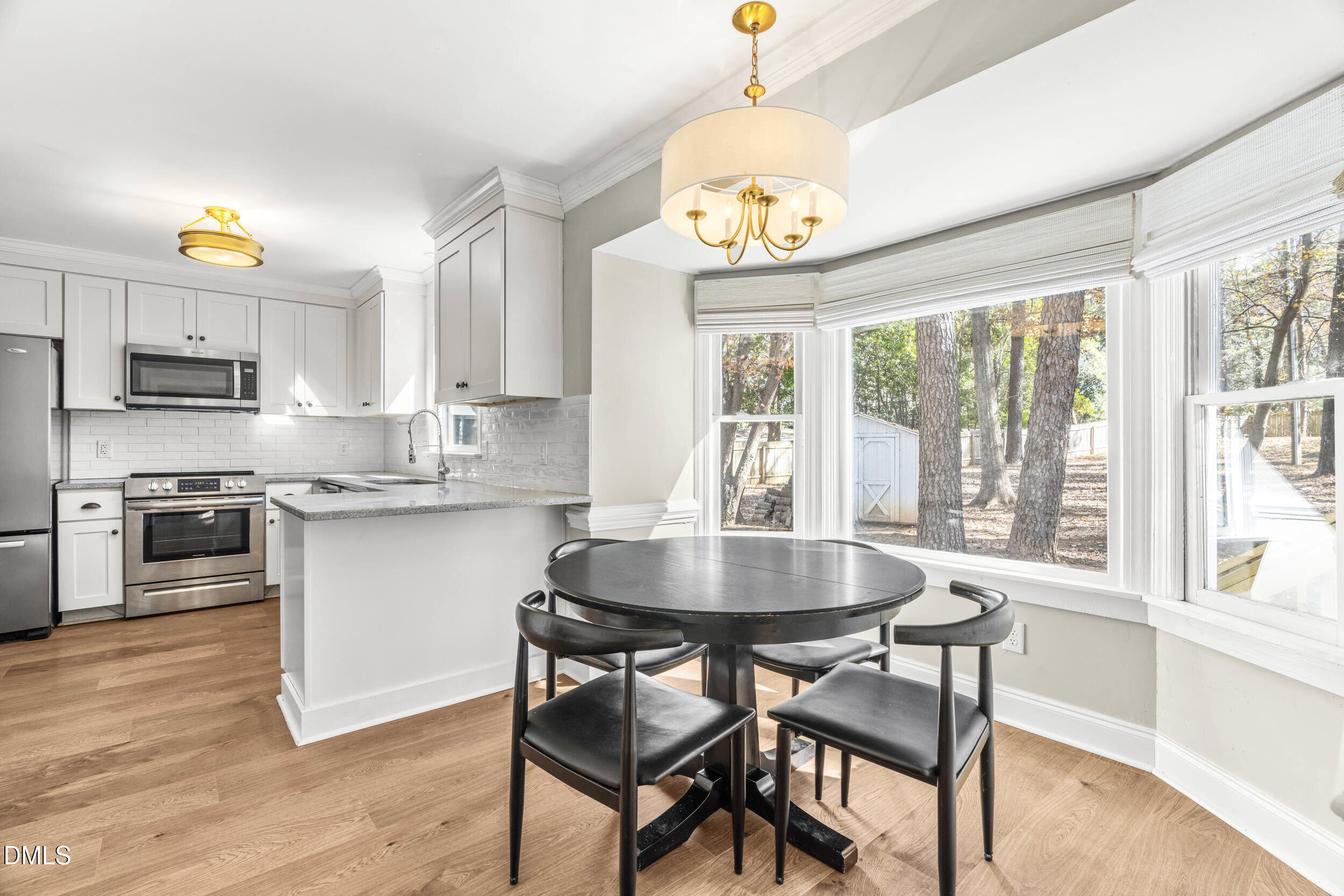 10716 Marthas Way Raleigh, NC 27615 - Photo 9 of 32 a kitchen with a stove a sink dishwasher a dining table and chairs with wooden floor