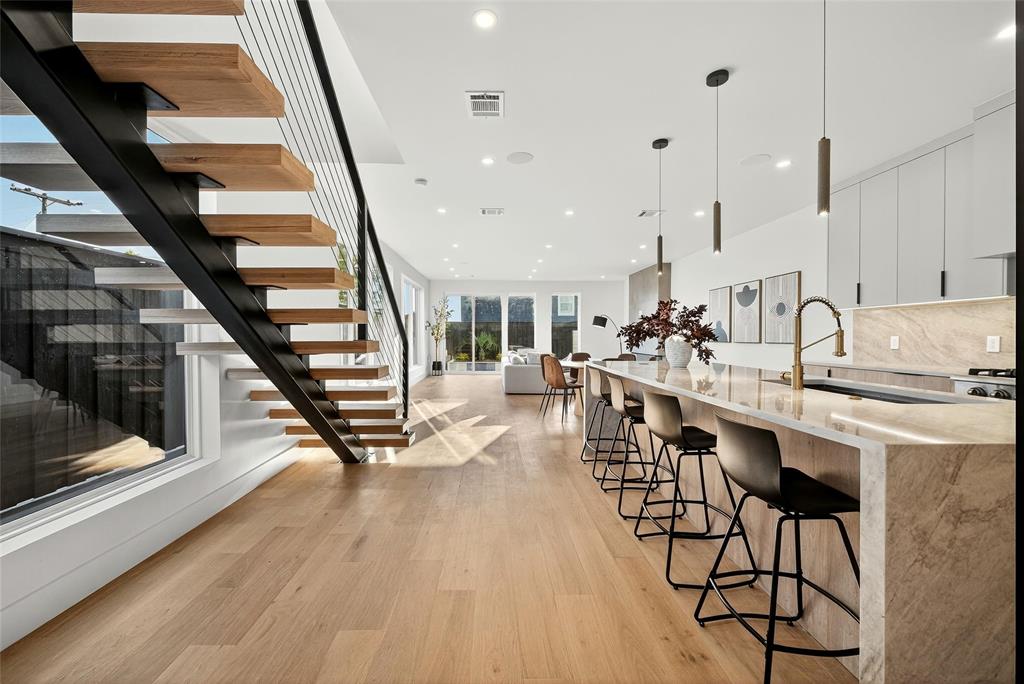 a dining hall with stainless steel appliances kitchen island granite countertop a stove top oven a sink with the island and chairs