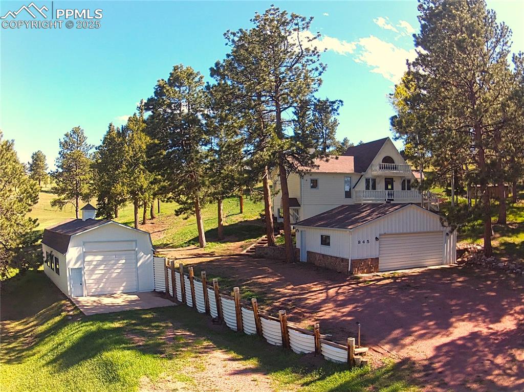 a view of a white house next to a yard with large trees