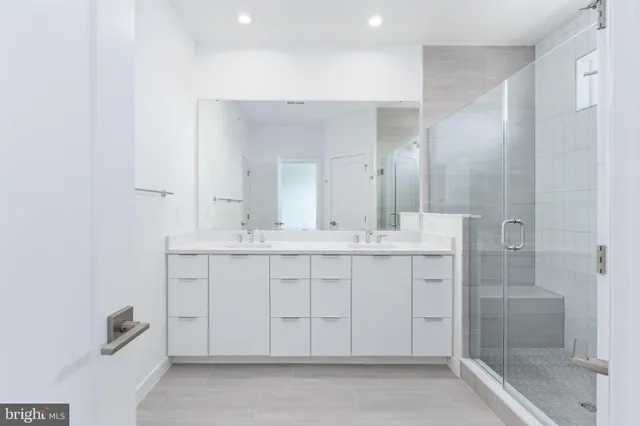 a bathroom with a double vanity sink mirror and shower