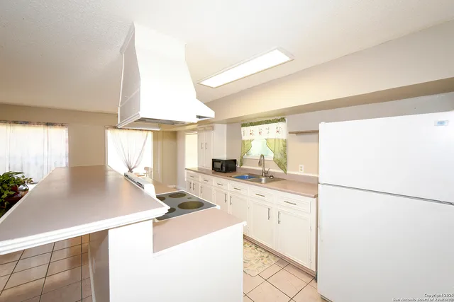 a kitchen with a sink a stove and white cabinets