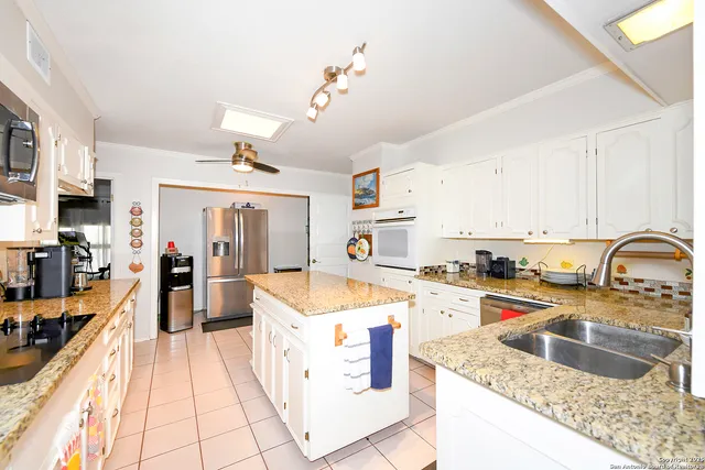 a large kitchen with kitchen island a large counter space a sink appliances and cabinets
