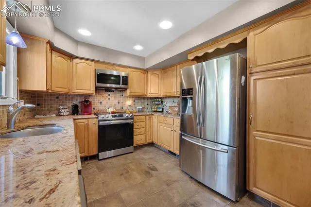 a kitchen with granite countertop a refrigerator stove top oven a sink and dishwasher