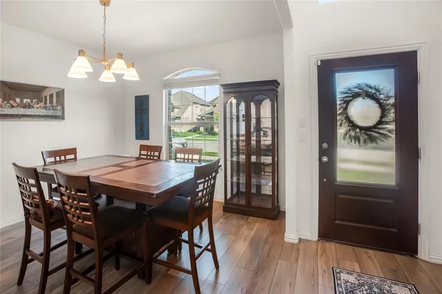 a dining room with wooden floor a chandelier a wooden table and chairs